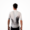 Maillot manches courtes blanc et noir, avec détails techniques visibles, porté par un cycliste vu de dos.