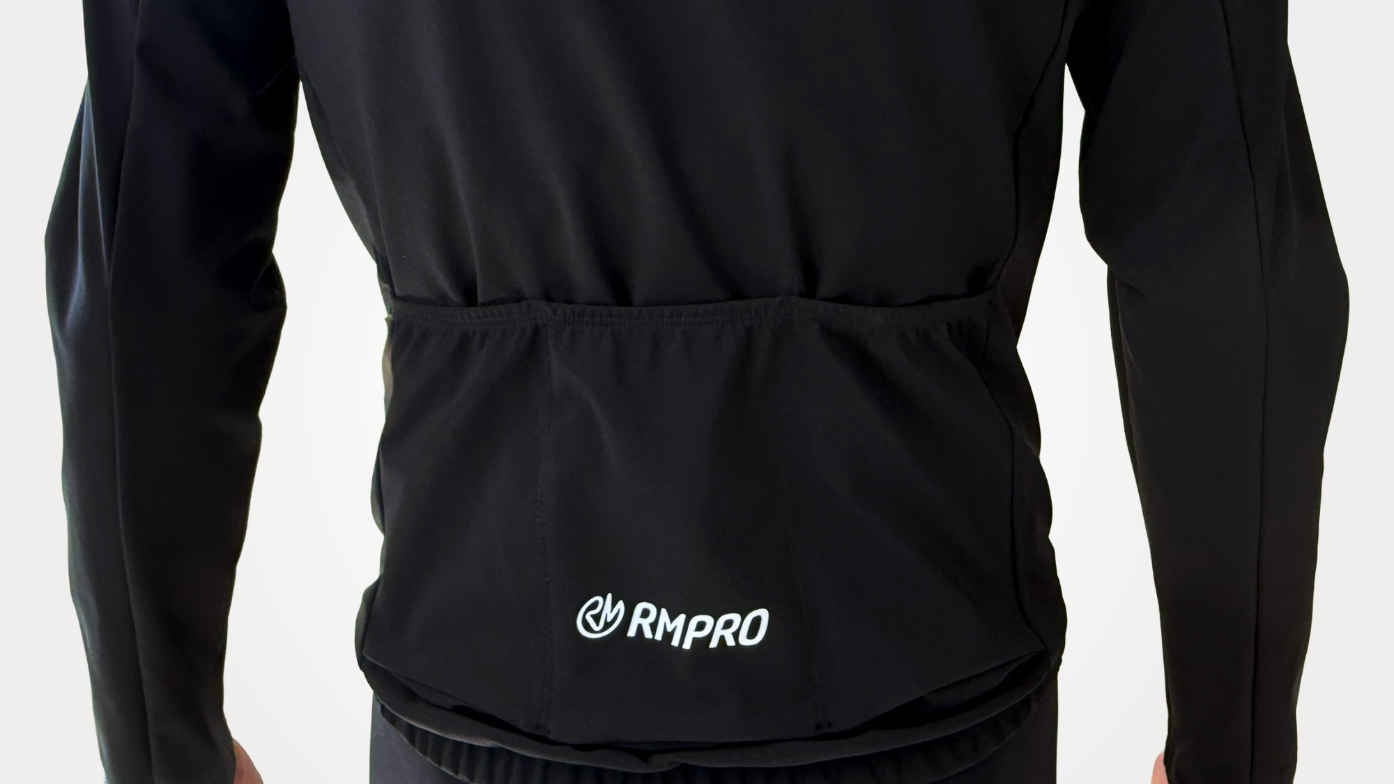 Veste technique noire avec poches arrière, logo RMPRO visible.