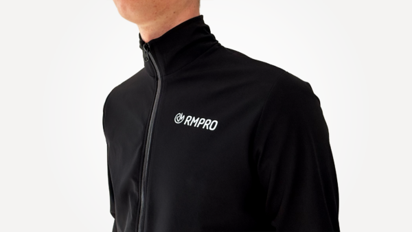 Veste technique noire avec logo RM PRO, conçue pour le cyclisme et offrant une protection contre le vent.