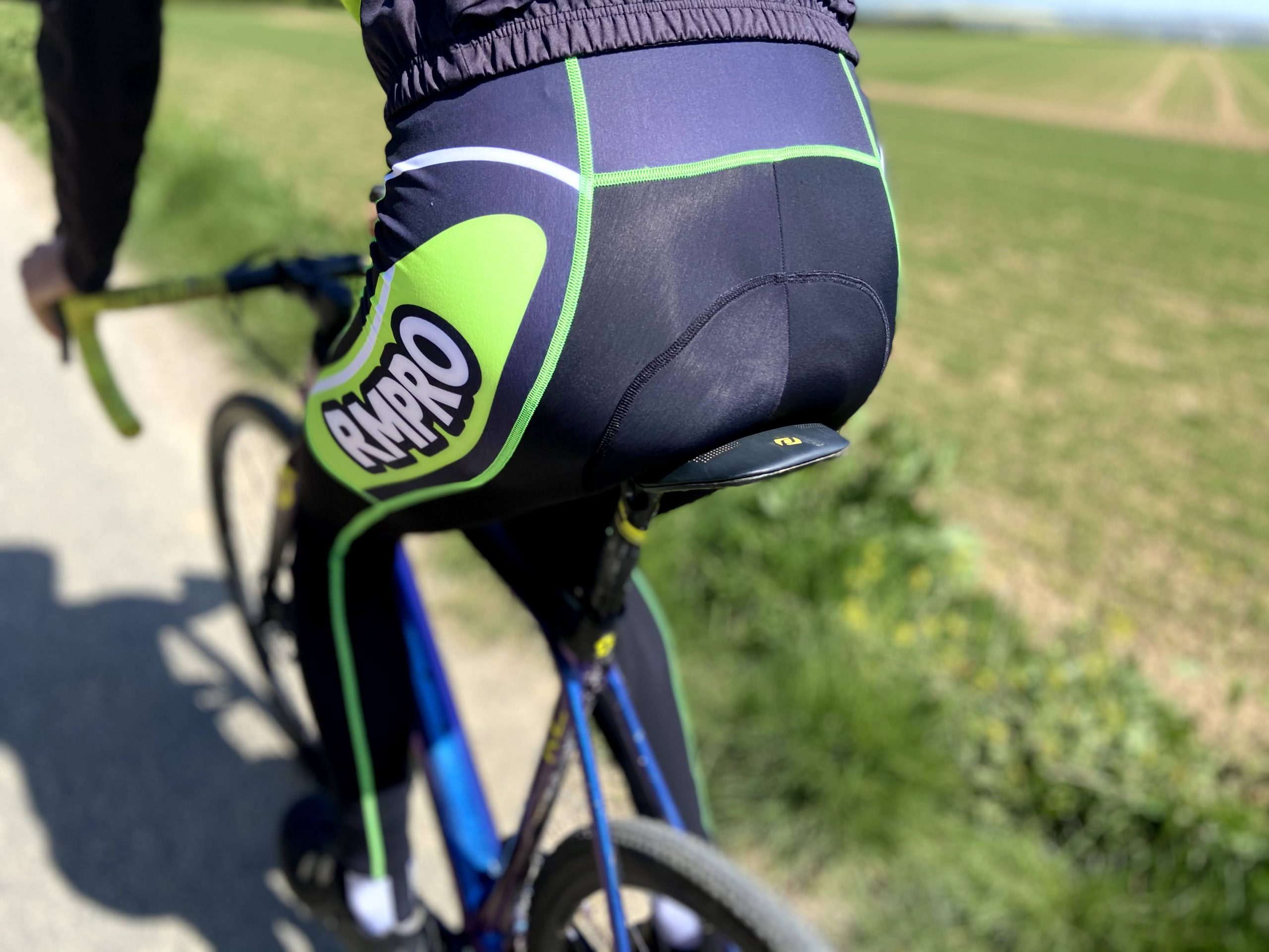 Cycliste en tenue personnalisée bleue levant les bras en signe de victoire devant un public enthousiaste.