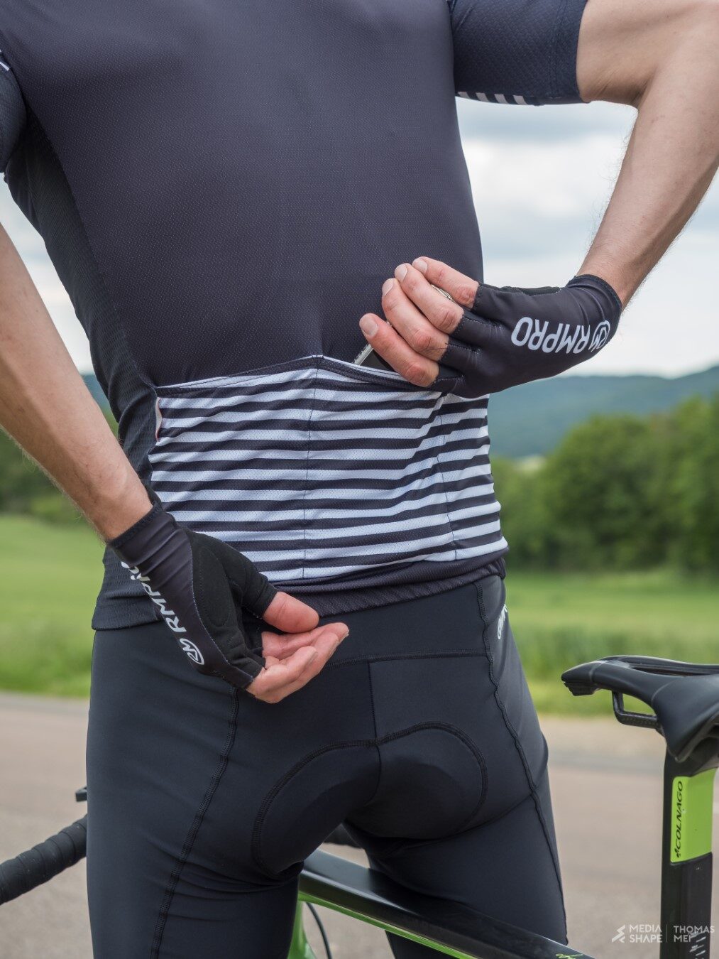 Cycliste en tenue personnalisée bleue levant les bras en signe de victoire devant un public enthousiaste.