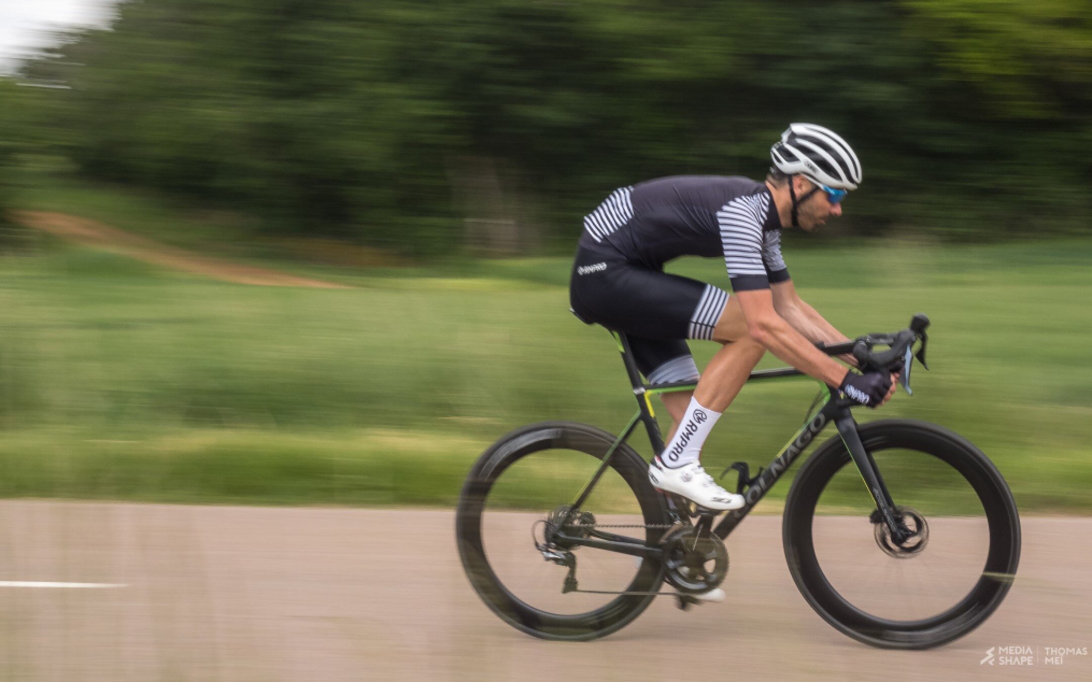 Cycliste en tenue personnalisée bleue levant les bras en signe de victoire devant un public enthousiaste.