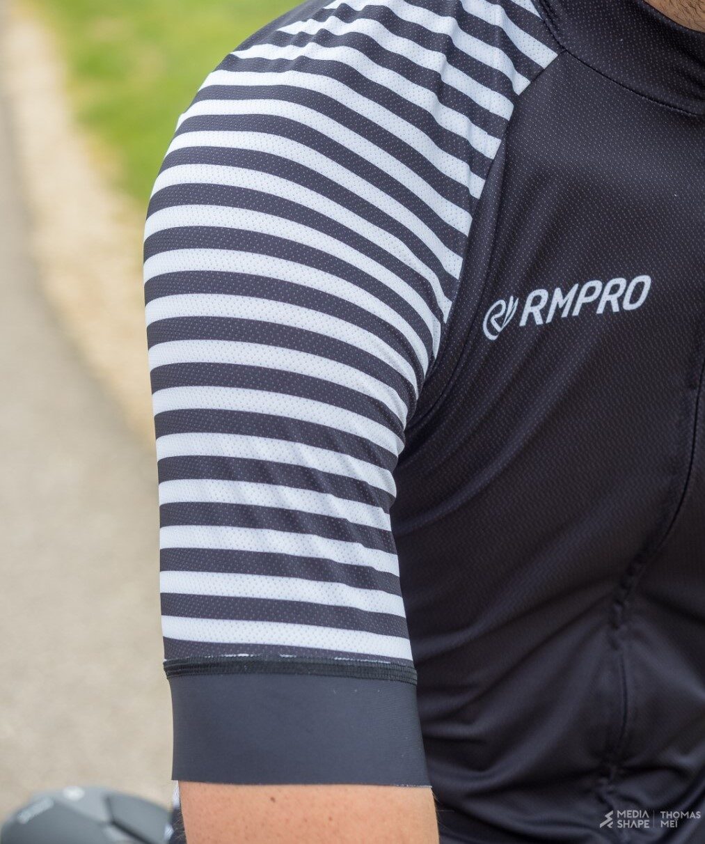Cycliste en tenue personnalisée bleue levant les bras en signe de victoire devant un public enthousiaste.