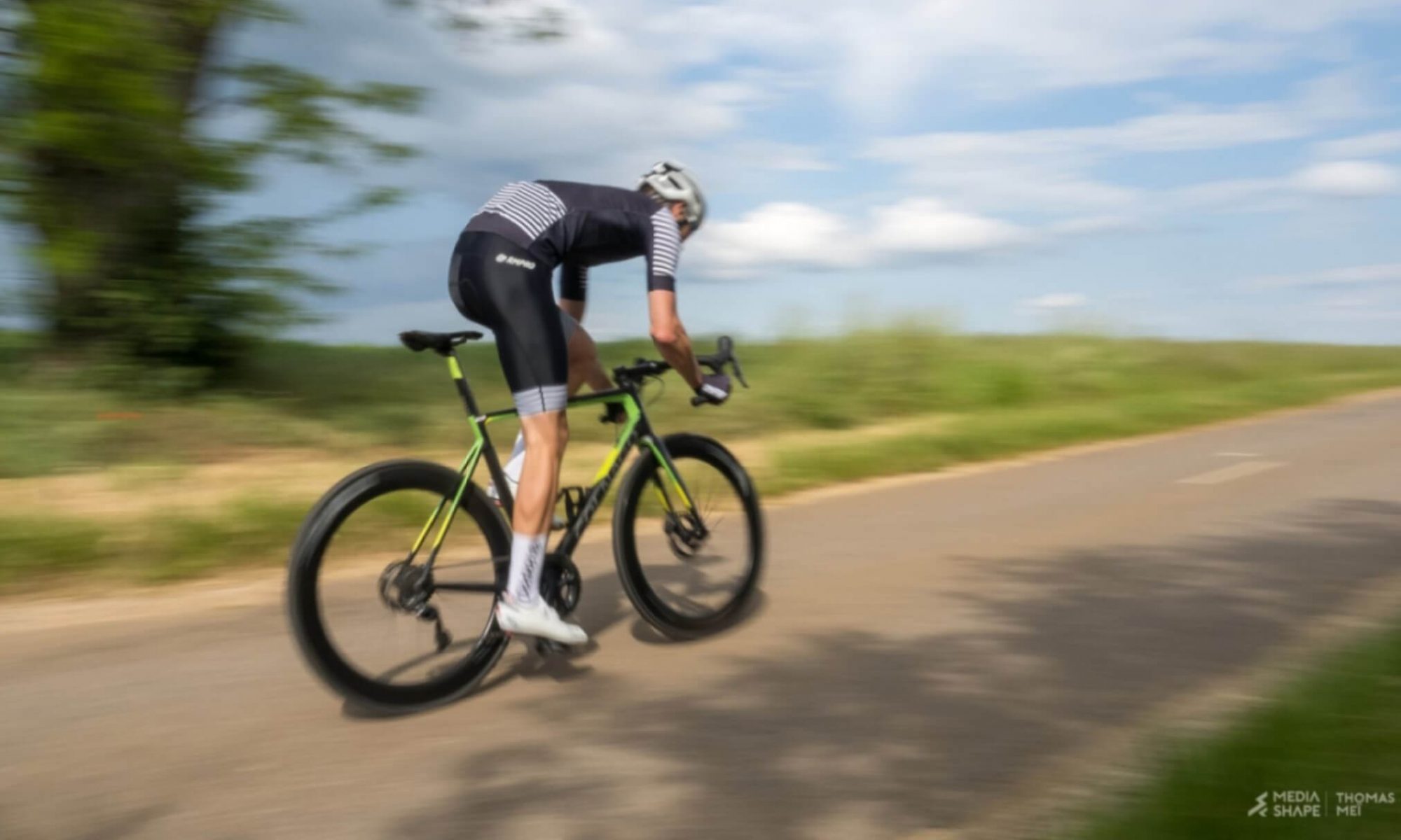 Cycliste en tenue avec maillot à rayures sur route sinueuse.