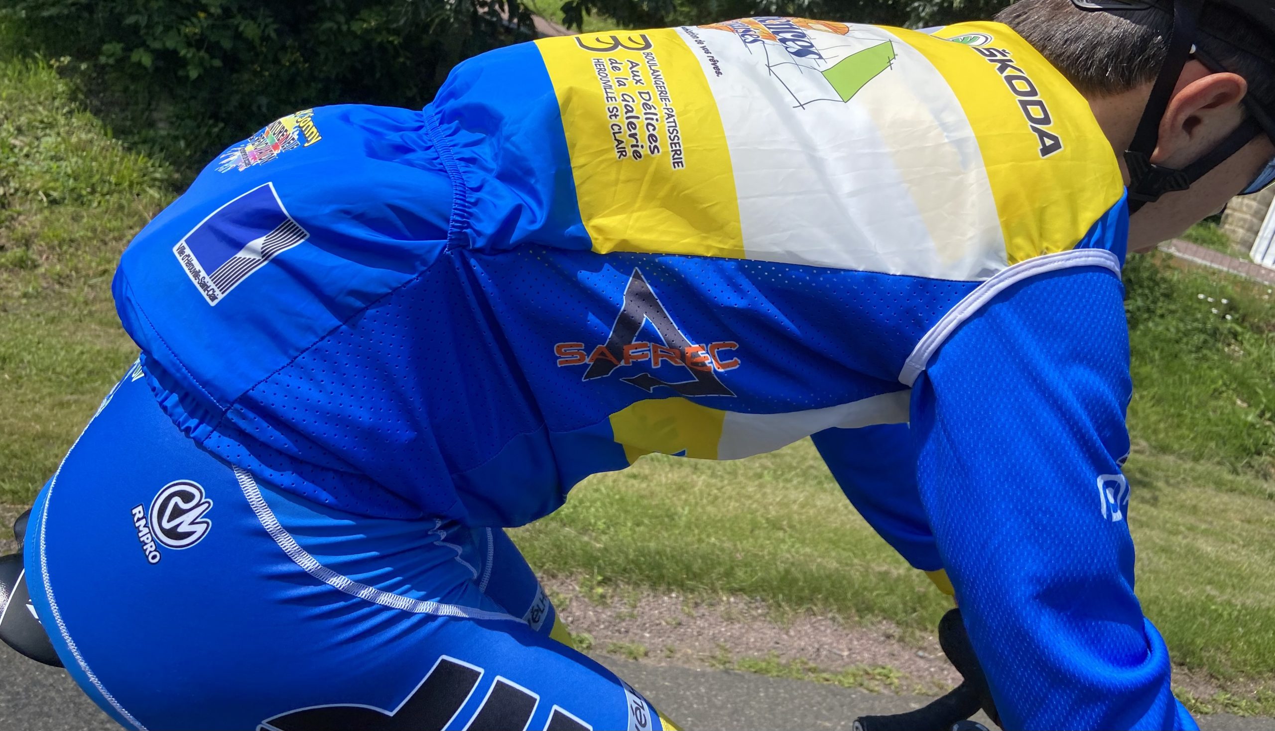 Cycliste en tenue personnalisée bleue levant les bras en signe de victoire devant un public enthousiaste.
