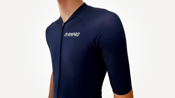 Maillot manches courtes bleu marine avec fermeture éclair, tissu technique visible.