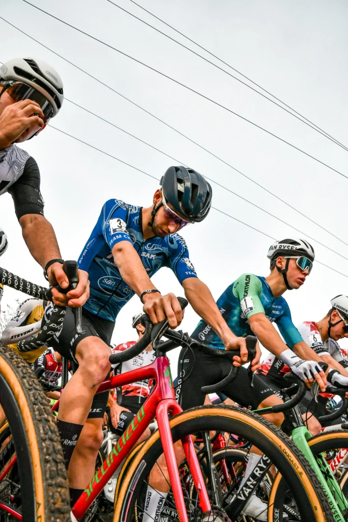 Cyclistes en position de départ sur leurs vélos, vêtus de maillots colorés et personnalisés pour la compétition.