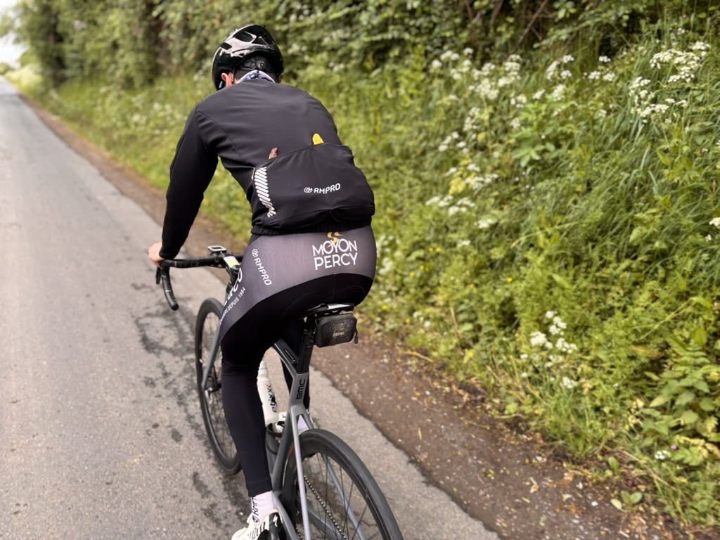 Cycliste en tenue personnalisée bleue levant les bras en signe de victoire devant un public enthousiaste.