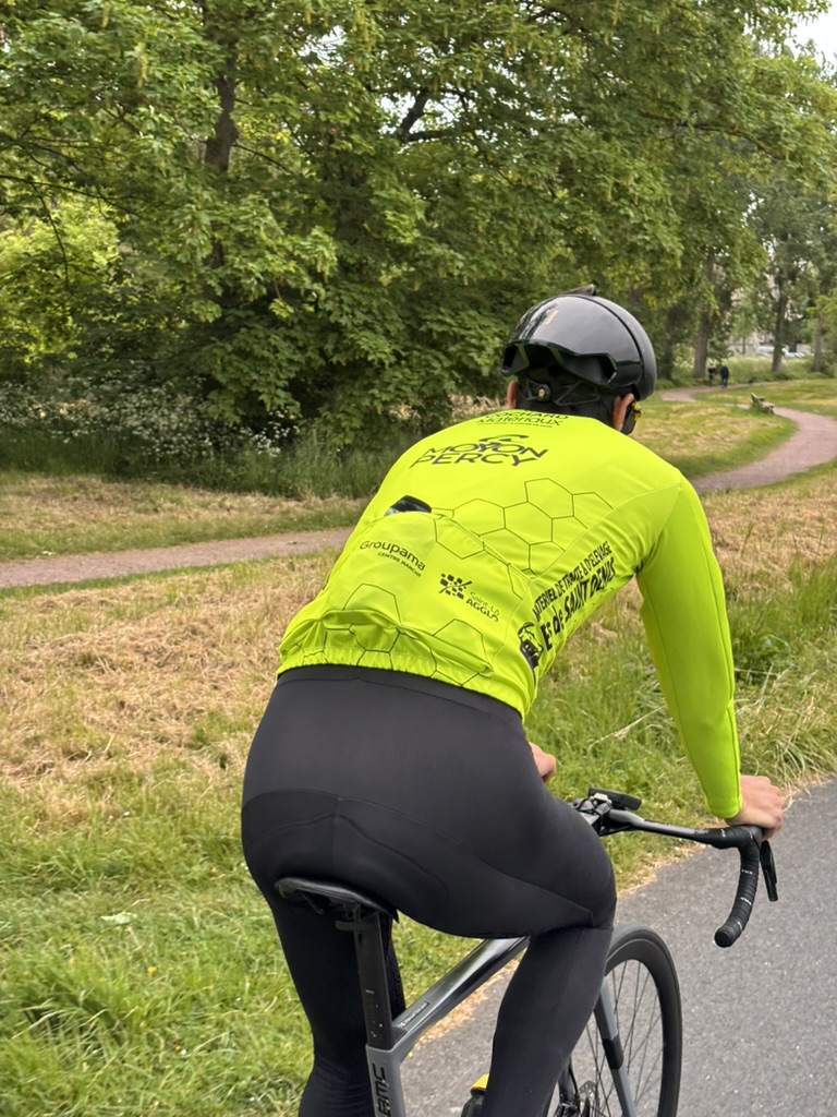 Cycliste en tenue personnalisée bleue levant les bras en signe de victoire devant un public enthousiaste.