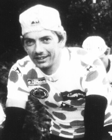 Cycliste portant un maillot à pois et une casquette, en pleine préparation pour une course.